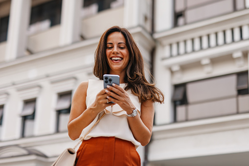 Excited woman laughing while reading a message on her phone